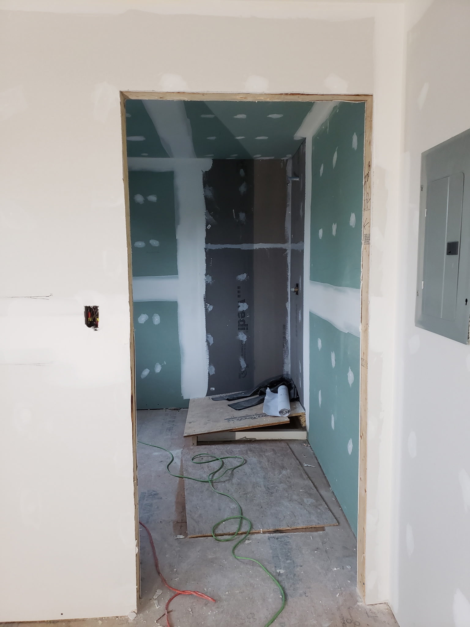 View through a doorway toward moisture-resistant drywall being taped and finished