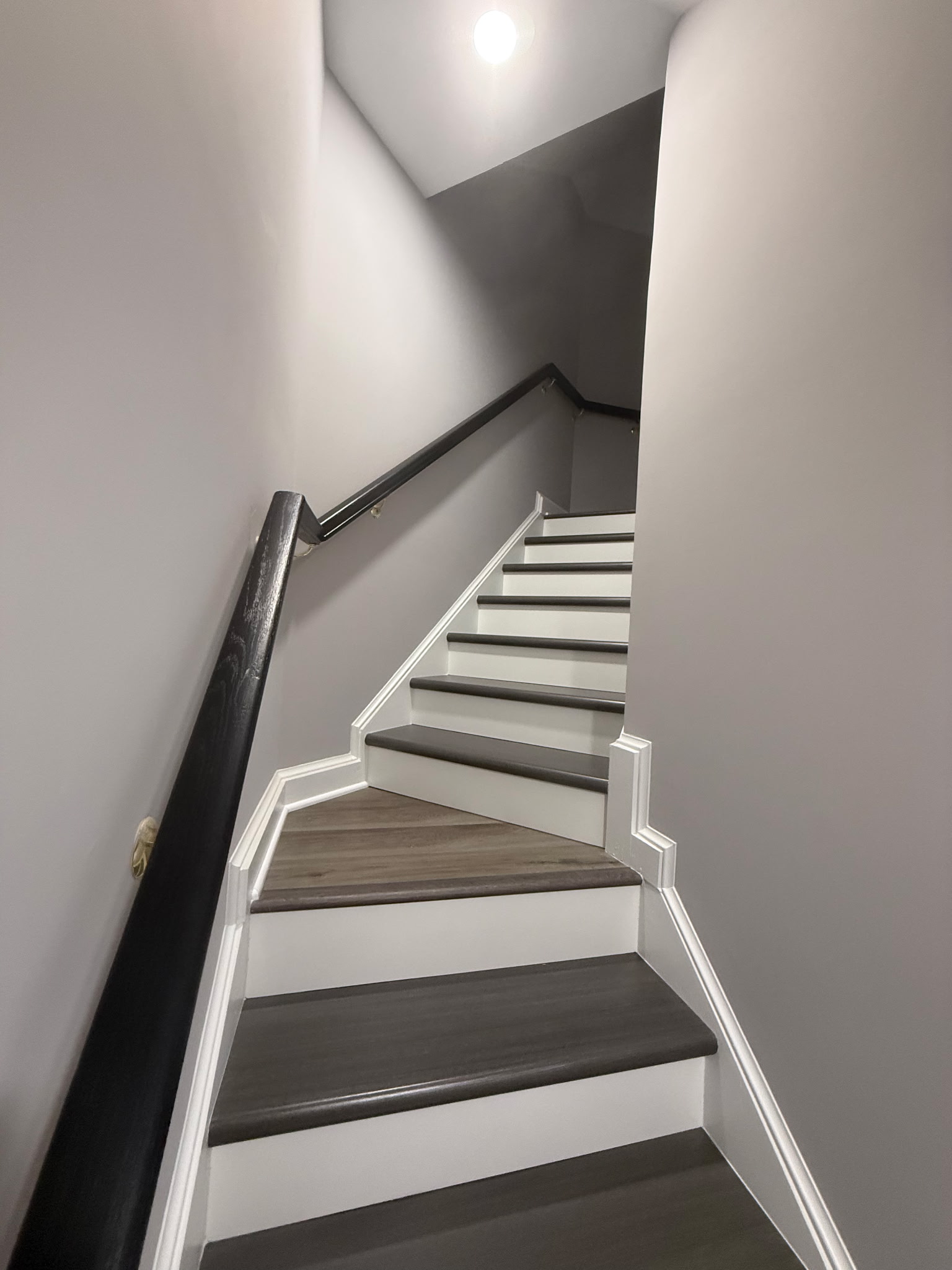 Upper view of a finished basement staircase with contrasting treads and white trim