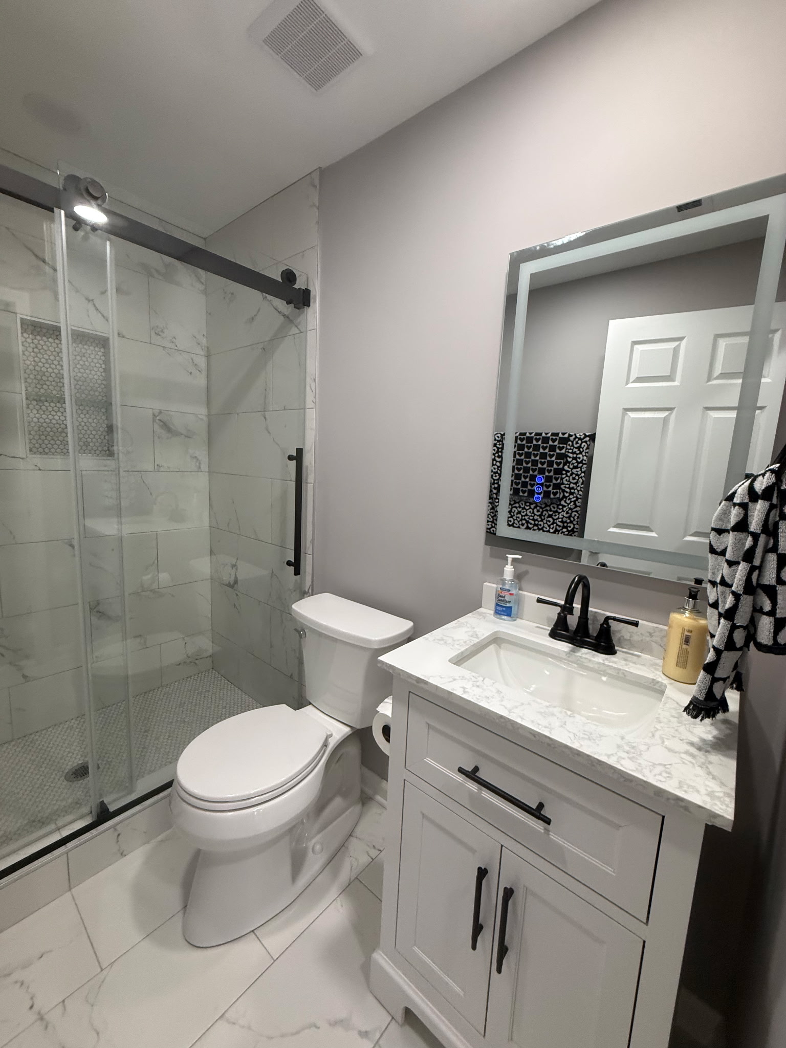Finished bathroom vanity, mirror, tiled shower, and black hardware
